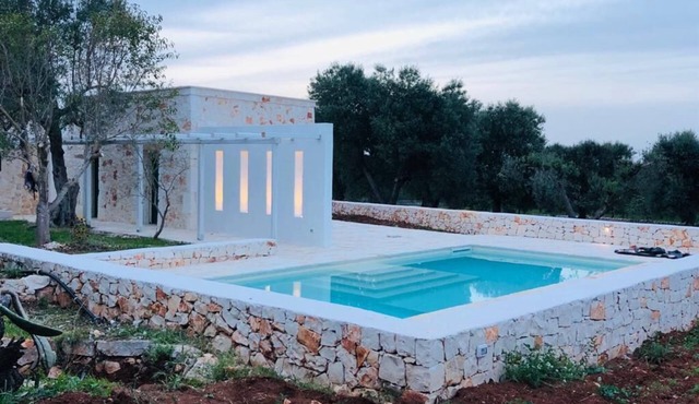 White stone typical apulian villa with barrel roof surrounded by olive trees. in Ostuni